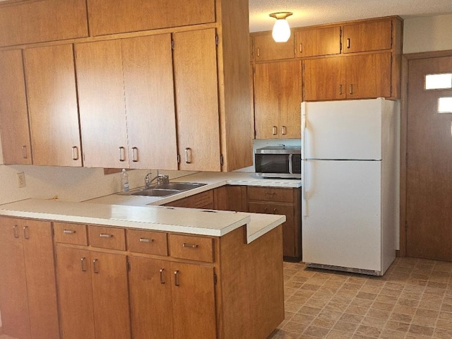 kitchen with sink, a textured ceiling, white refrigerator, and kitchen peninsula