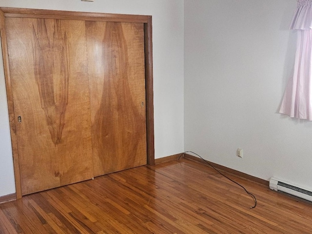 unfurnished bedroom featuring a closet, hardwood / wood-style floors, and a baseboard radiator