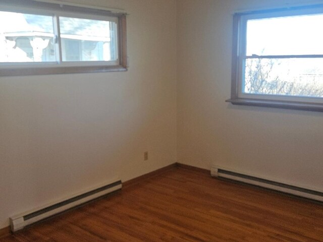 spare room featuring a wealth of natural light, dark hardwood / wood-style flooring, and a baseboard radiator