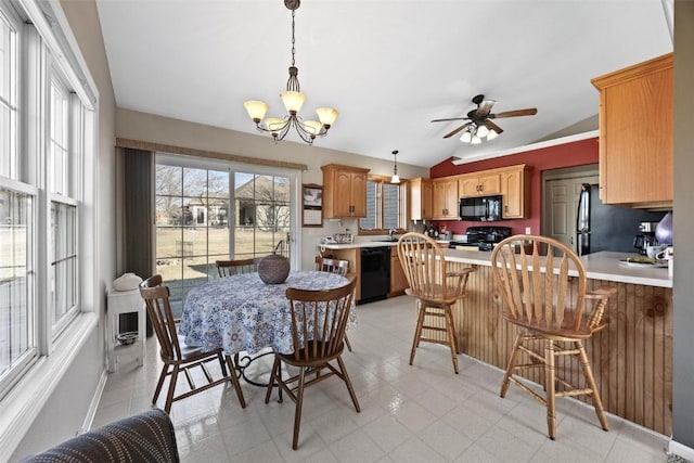 dining area featuring ceiling fan with notable chandelier, sink, and lofted ceiling