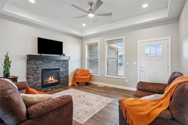 living room with ceiling fan, a fireplace, dark hardwood / wood-style floors, and a raised ceiling