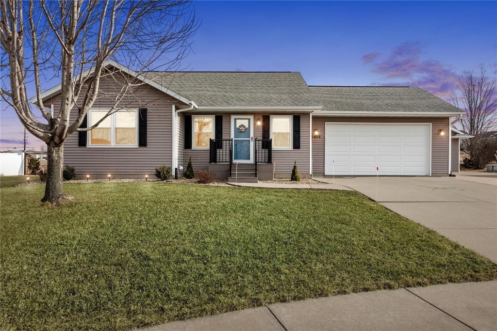 ranch-style house featuring a garage and a yard