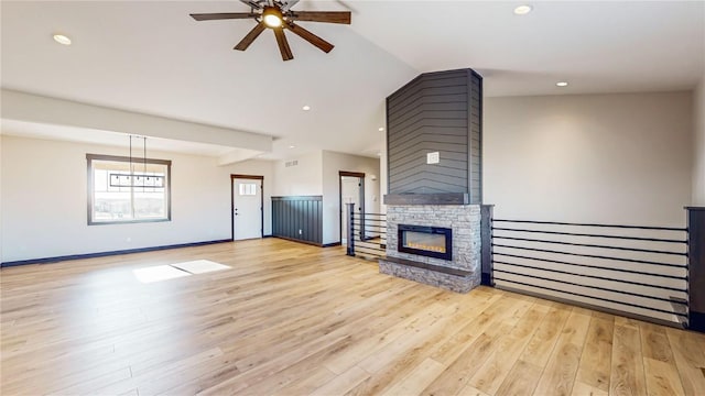 unfurnished living room with light wood-type flooring, ceiling fan, and a stone fireplace