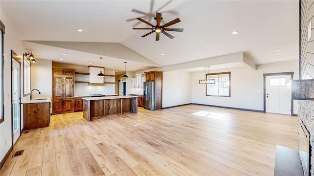 kitchen featuring stainless steel fridge, a center island, pendant lighting, light hardwood / wood-style flooring, and sink