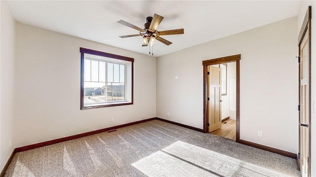 unfurnished bedroom with ceiling fan, light colored carpet, and connected bathroom