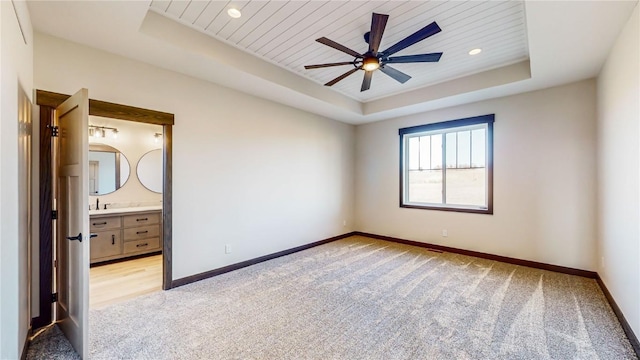 unfurnished bedroom featuring ceiling fan, light colored carpet, ensuite bath, a raised ceiling, and wooden ceiling