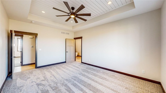 unfurnished bedroom featuring a raised ceiling, light colored carpet, and wooden ceiling