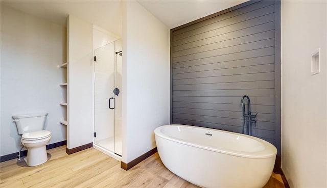 full bath featuring toilet, a stall shower, a freestanding bath, and wood finished floors
