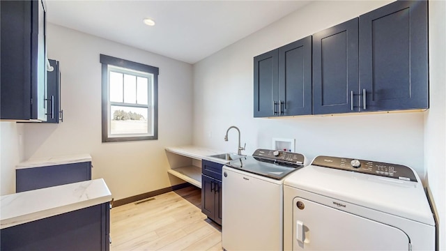 laundry area featuring light hardwood / wood-style flooring, independent washer and dryer, sink, and cabinets