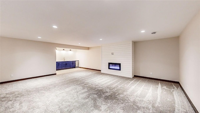 unfurnished living room with light carpet and a large fireplace