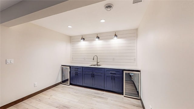 bar featuring sink, light hardwood / wood-style flooring, blue cabinets, and wine cooler