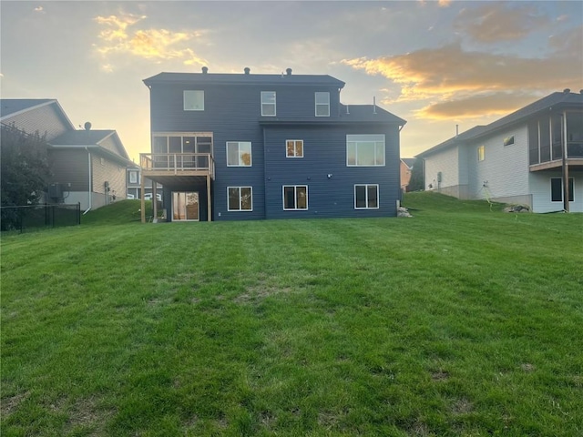 back house at dusk featuring a lawn