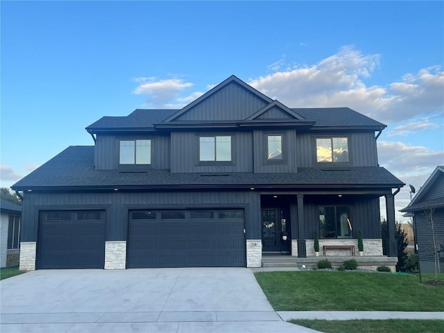 view of front of home featuring a front yard, covered porch, and a garage