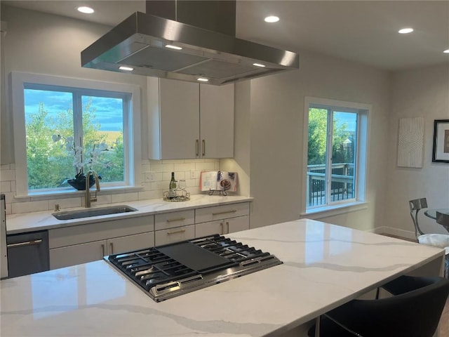 kitchen featuring island exhaust hood, stainless steel appliances, white cabinets, light stone counters, and sink