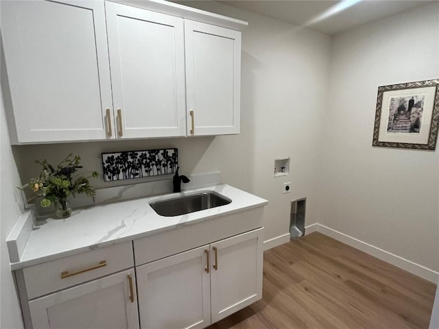 laundry area with cabinets, light hardwood / wood-style floors, sink, hookup for a washing machine, and hookup for an electric dryer