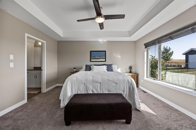 carpeted bedroom featuring ceiling fan, connected bathroom, and a tray ceiling