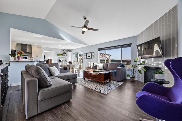 living room with ceiling fan, a large fireplace, lofted ceiling, and dark hardwood / wood-style floors