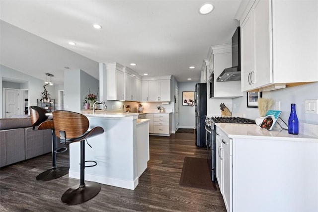 kitchen featuring wall chimney exhaust hood, white cabinetry, dark hardwood / wood-style floors, kitchen peninsula, and stainless steel range with gas stovetop