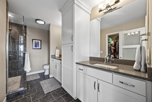 bathroom featuring toilet, a tile shower, and vanity