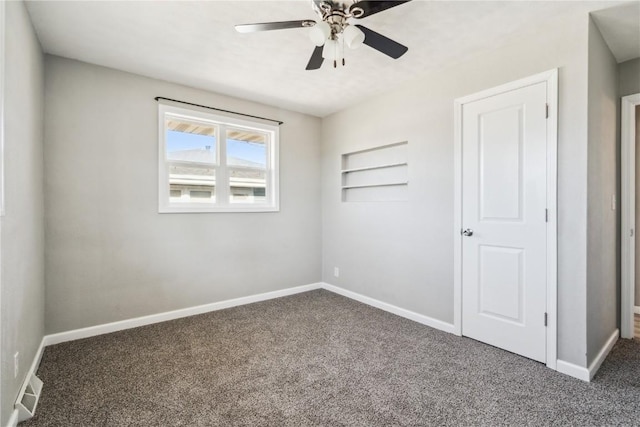 empty room with ceiling fan and dark colored carpet