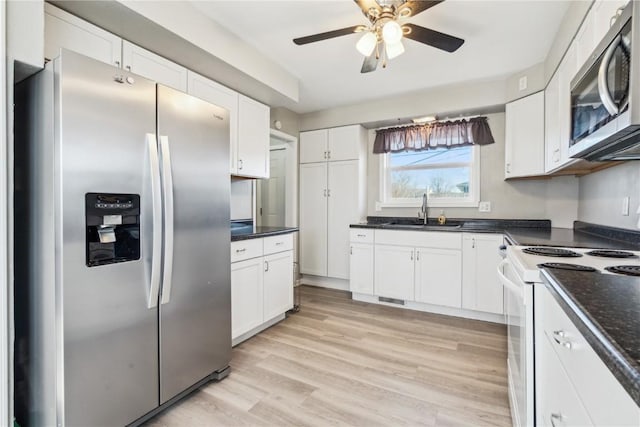 kitchen with ceiling fan, appliances with stainless steel finishes, sink, white cabinets, and light hardwood / wood-style floors