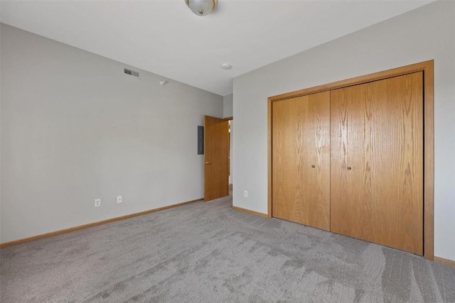 unfurnished bedroom with a closet and light colored carpet