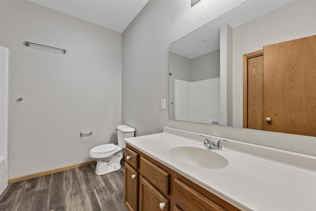 bathroom with hardwood / wood-style floors, toilet, vanity, and walk in shower