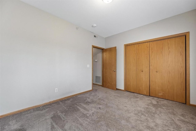 unfurnished bedroom featuring light colored carpet and a closet