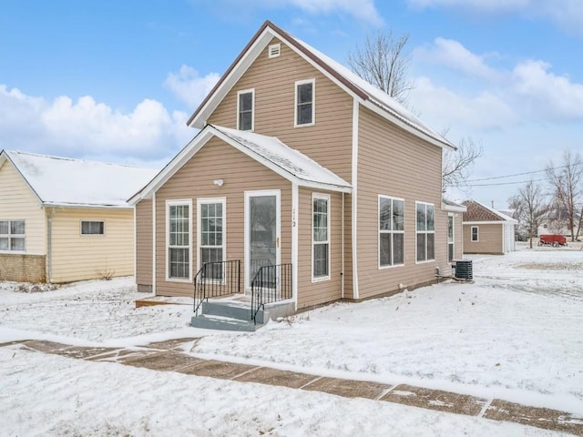 snow covered rear of property featuring central AC