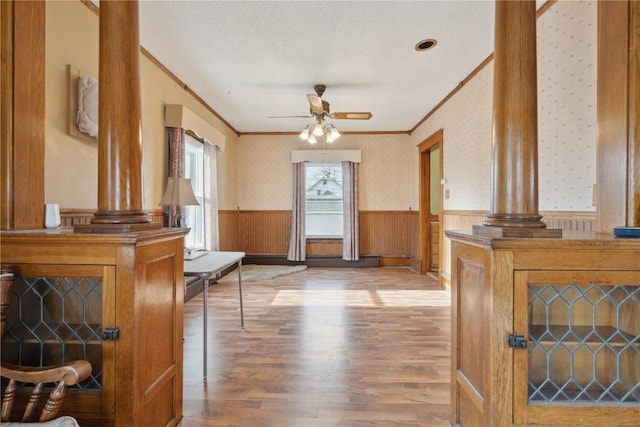 interior space with crown molding, ceiling fan, hardwood / wood-style floors, and ornate columns