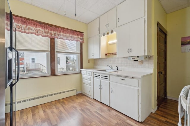 kitchen featuring baseboard heating, sink, light hardwood / wood-style flooring, and white cabinets