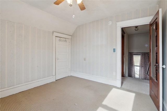 empty room with ceiling fan, light colored carpet, and lofted ceiling