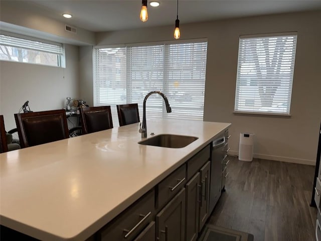 kitchen with sink, a kitchen island with sink, hanging light fixtures, and dark hardwood / wood-style flooring