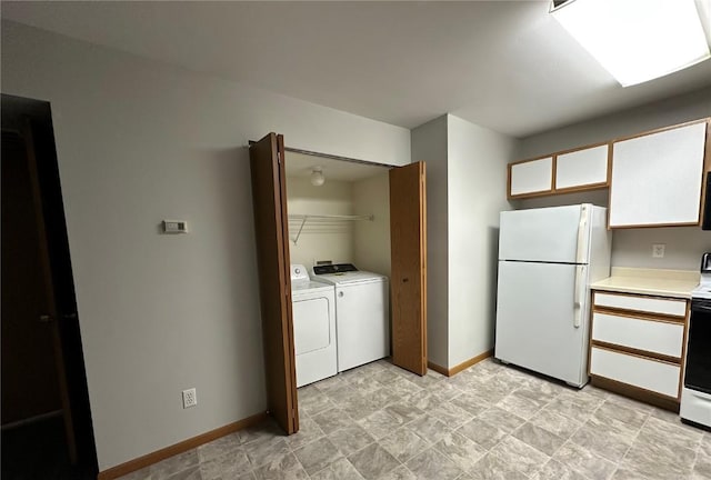 kitchen featuring white appliances, washing machine and clothes dryer, and white cabinets