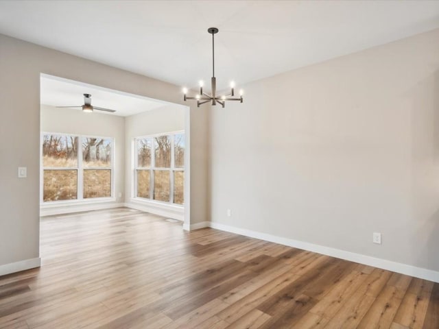 unfurnished dining area featuring ceiling fan with notable chandelier and light hardwood / wood-style floors