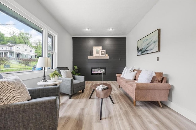 living room featuring light hardwood / wood-style flooring, a wealth of natural light, and a large fireplace