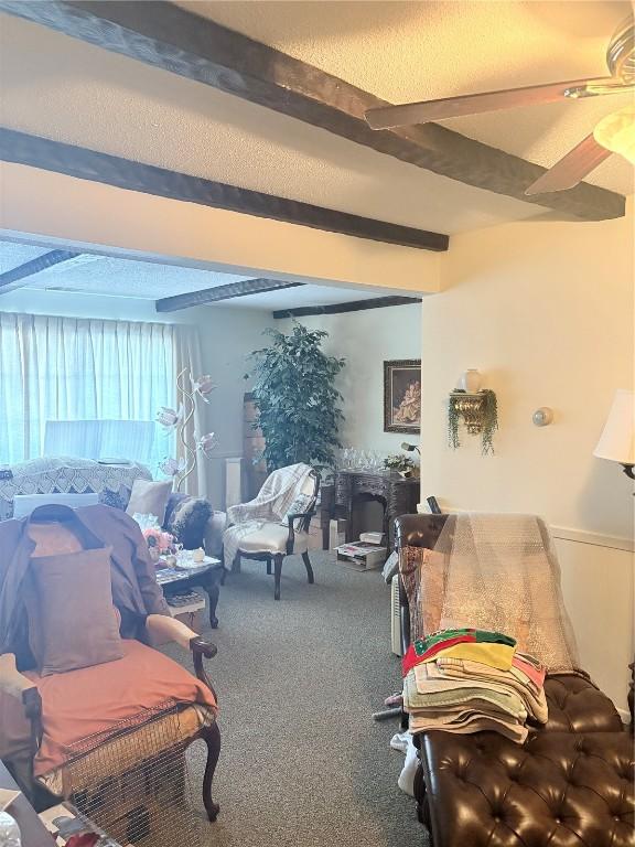 carpeted living room featuring beamed ceiling