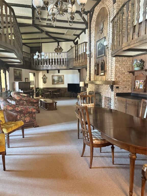 dining space featuring carpet floors, high vaulted ceiling, beamed ceiling, and a chandelier