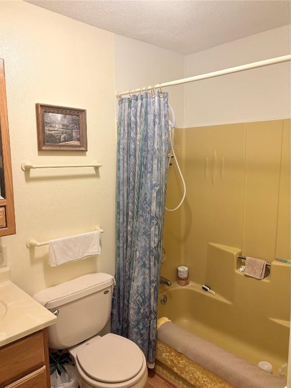 full bathroom with toilet, vanity, shower / bathtub combination with curtain, and a textured ceiling