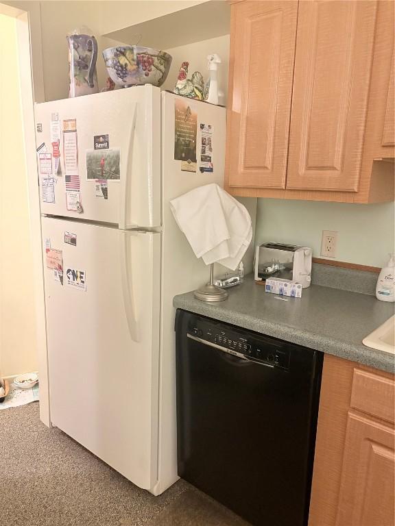 kitchen with white refrigerator, dishwasher, light brown cabinets, and dark carpet