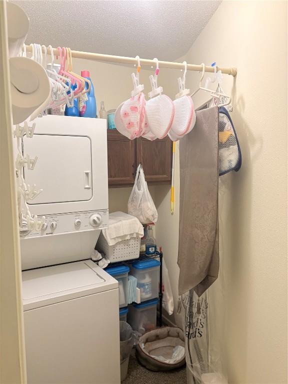 laundry room with stacked washer and clothes dryer and a textured ceiling