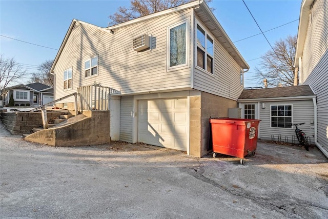 exterior space featuring a garage and a wall mounted air conditioner