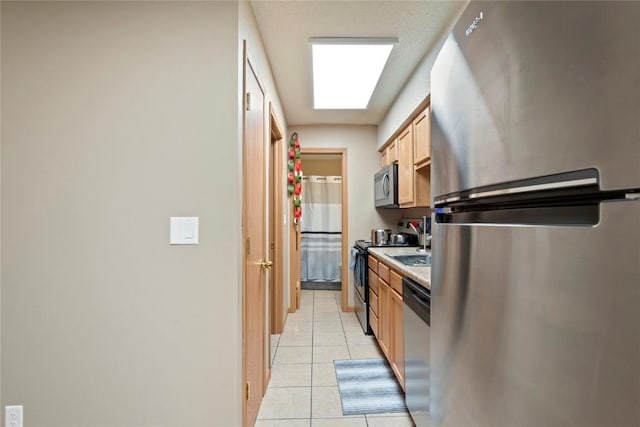 kitchen with stainless steel appliances, light brown cabinets, and light tile patterned floors