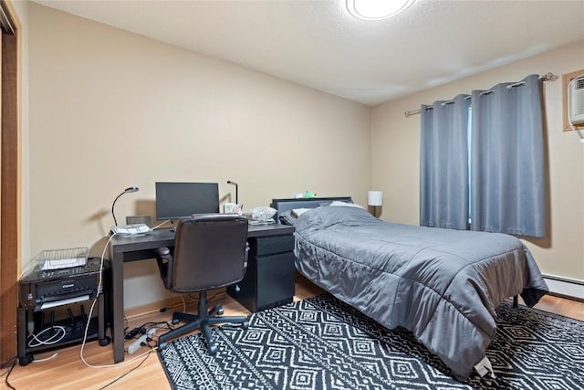 bedroom featuring baseboard heating and hardwood / wood-style floors