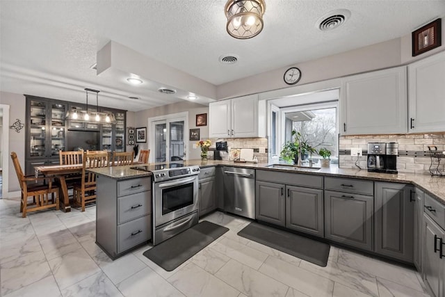 kitchen with decorative light fixtures, gray cabinets, kitchen peninsula, stainless steel appliances, and white cabinets