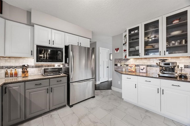 kitchen featuring white cabinetry, stainless steel fridge, and dark stone counters