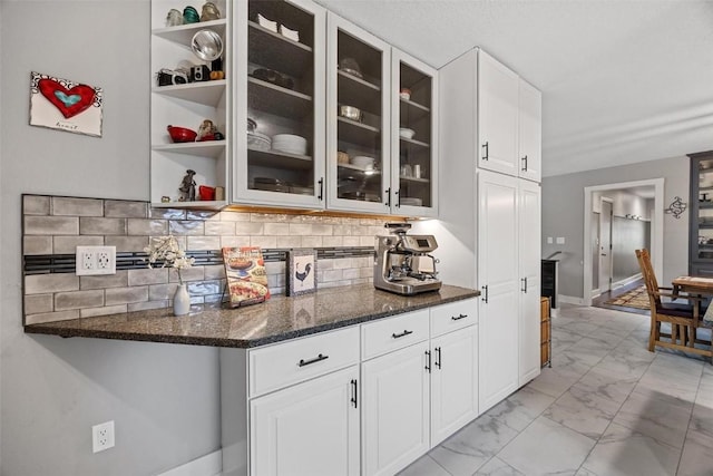 kitchen featuring tasteful backsplash, white cabinetry, and dark stone countertops