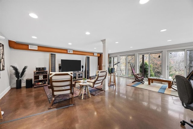 living room featuring concrete flooring and decorative columns