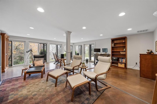 living area with concrete flooring and ornate columns