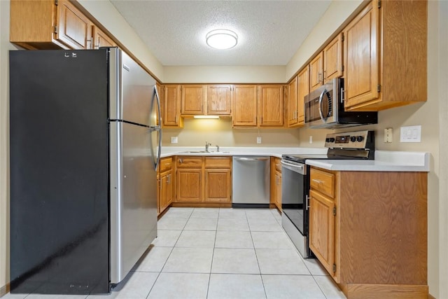 kitchen with sink, light tile patterned floors, a textured ceiling, and appliances with stainless steel finishes